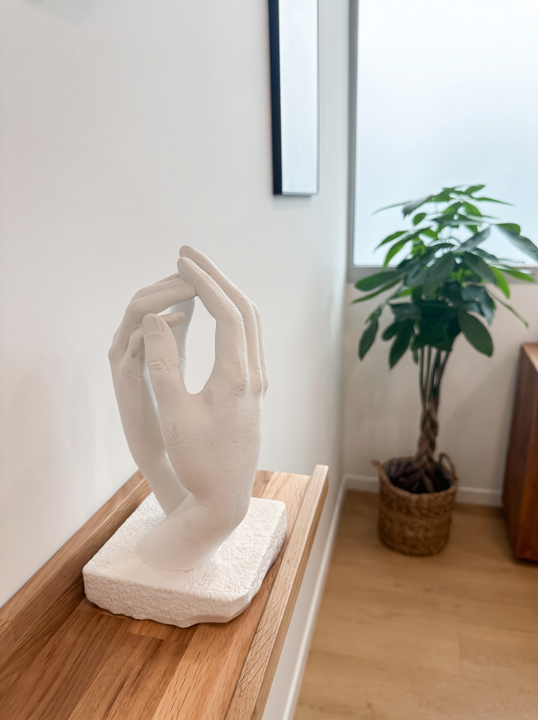 Sculpture de mains blanches posée sur une étagère en chêne dans le cabinet de Corentin Gaucher, ostéopathe à Rennes
